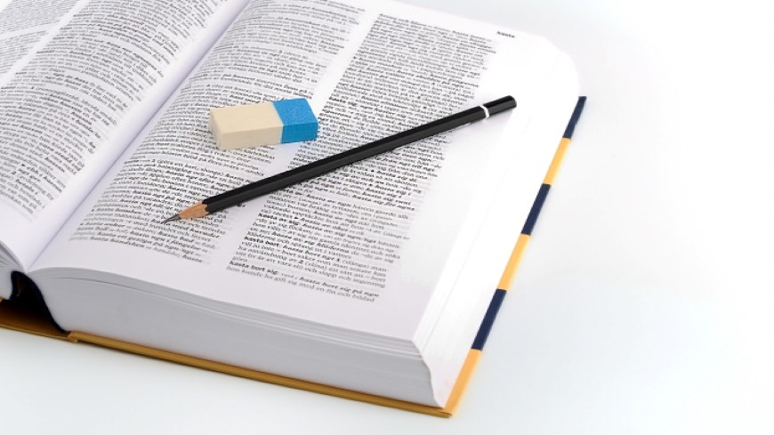 Uppslegen ordbok, penna och suddgummi