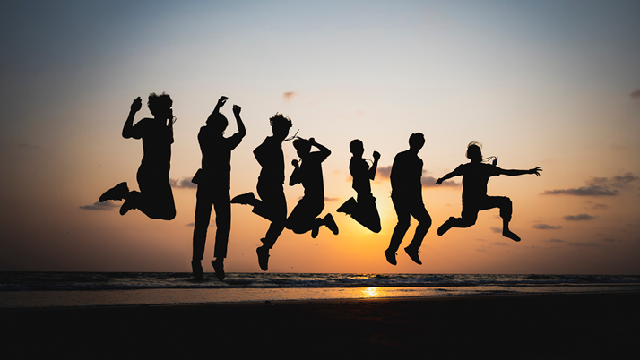 Sju tonåringar som hoppar i motljus